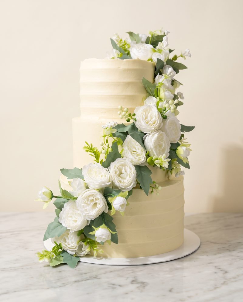 Wedding cake ivoire à trois étages, cascade de fleurs blanches