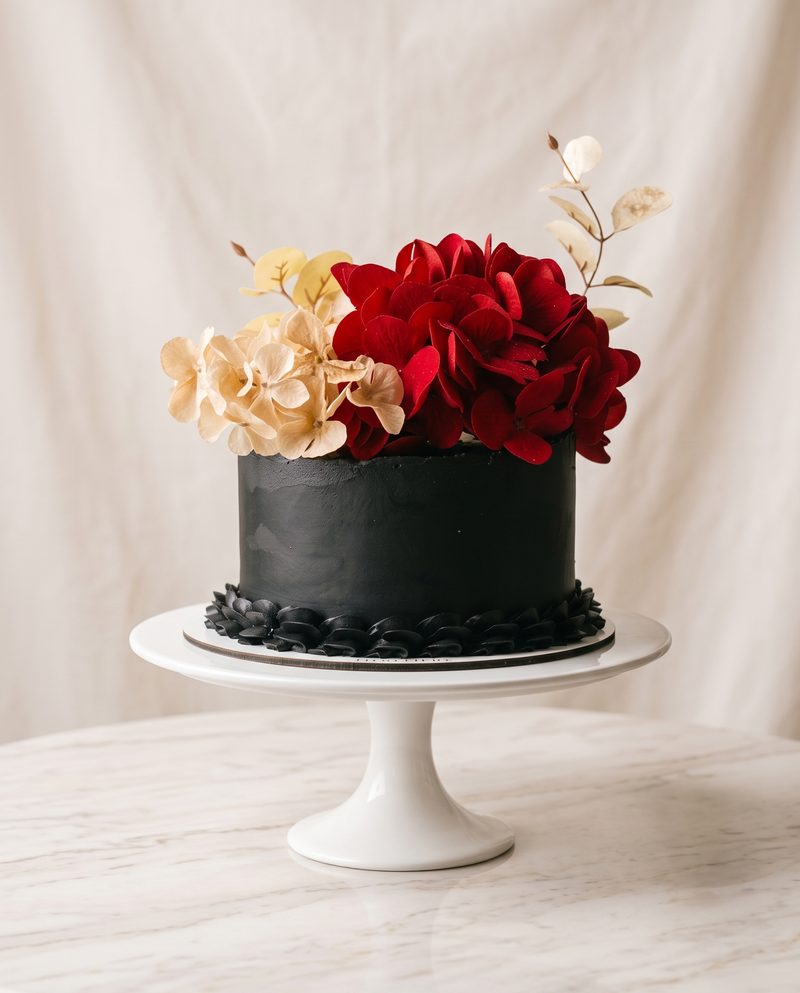 Gâteau d'anniversaire noir, hortensias rouges et eucalyptus doré